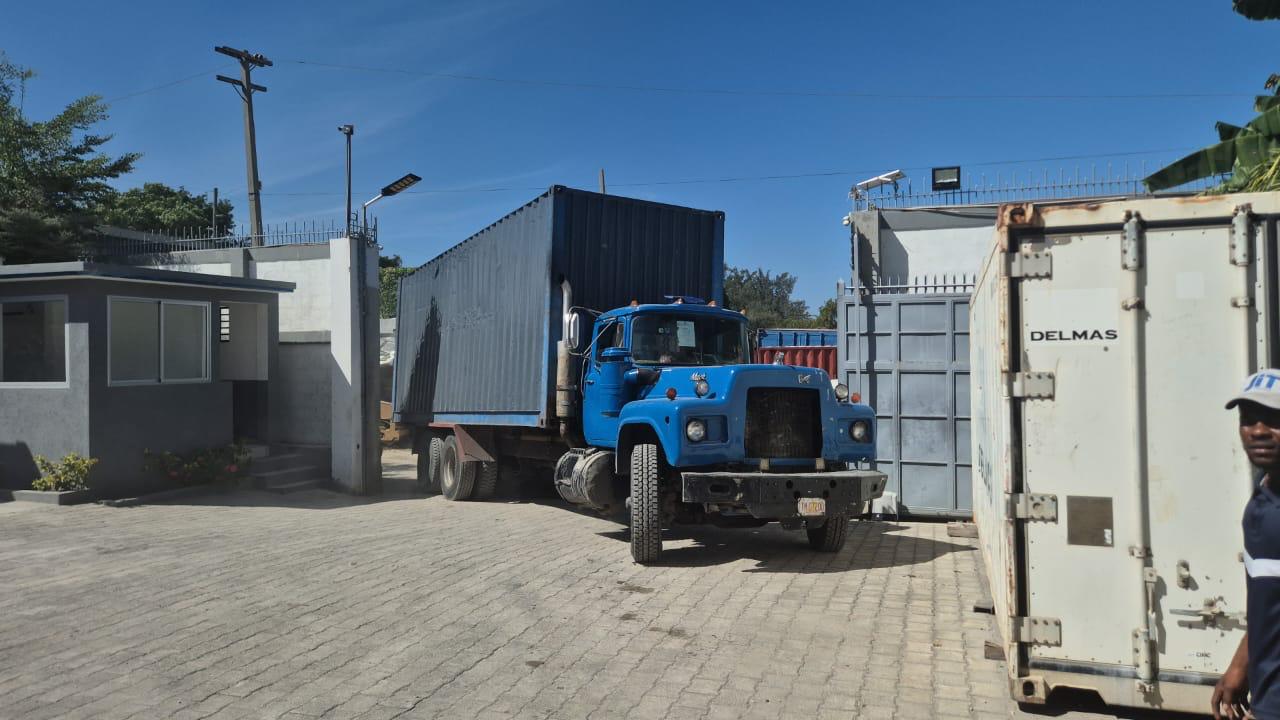 Truck hauling a shipping container through the port compound